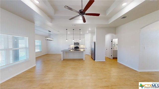 kitchen featuring pendant lighting, a center island with sink, white cabinets, light hardwood / wood-style floors, and stainless steel appliances