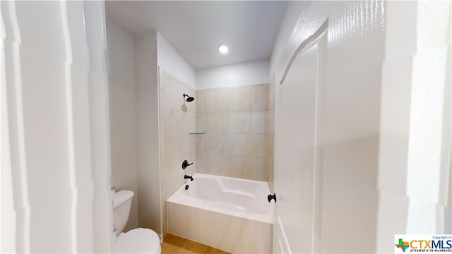 bathroom featuring hardwood / wood-style flooring, toilet, and tiled shower / bath