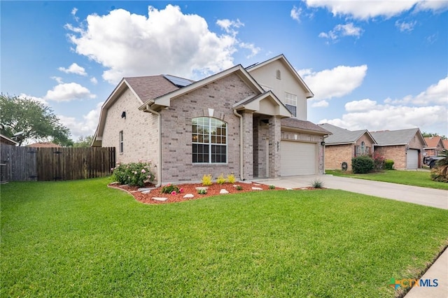 view of front of home with fence, brick siding, a front yard, roof mounted solar panels, and concrete driveway