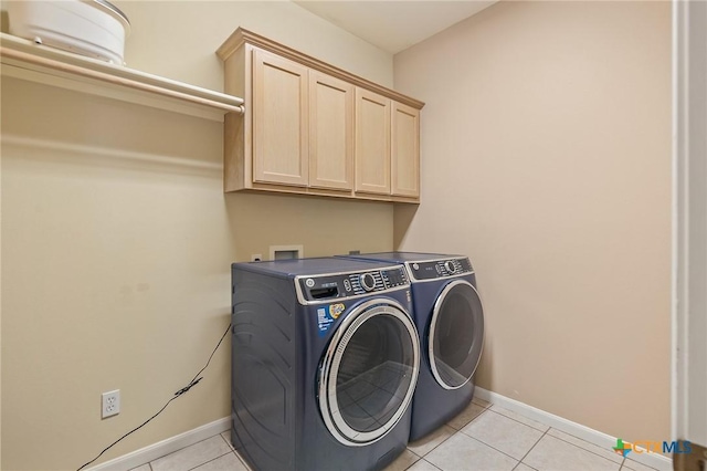 laundry area featuring cabinet space, light tile patterned flooring, baseboards, and washer and clothes dryer