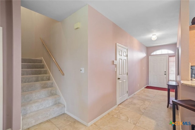 foyer with baseboards and stairs