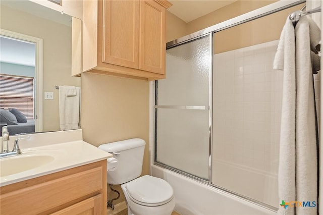 bathroom featuring vanity, enclosed tub / shower combo, and toilet