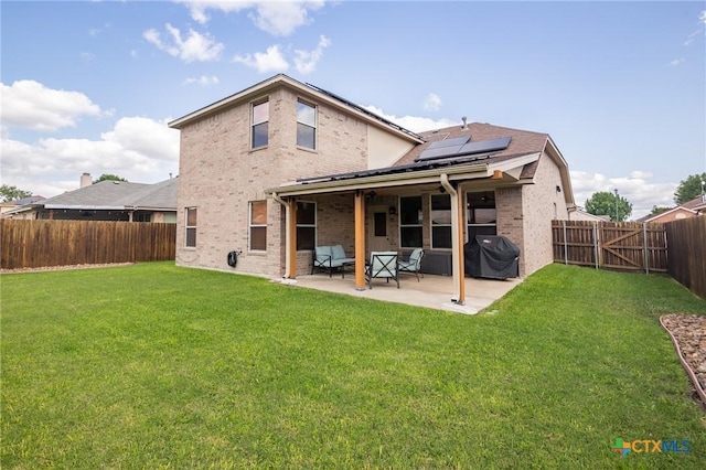 back of house with a patio, brick siding, roof mounted solar panels, and a fenced backyard