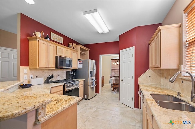 kitchen featuring light brown cabinetry, appliances with stainless steel finishes, a sink, and tasteful backsplash