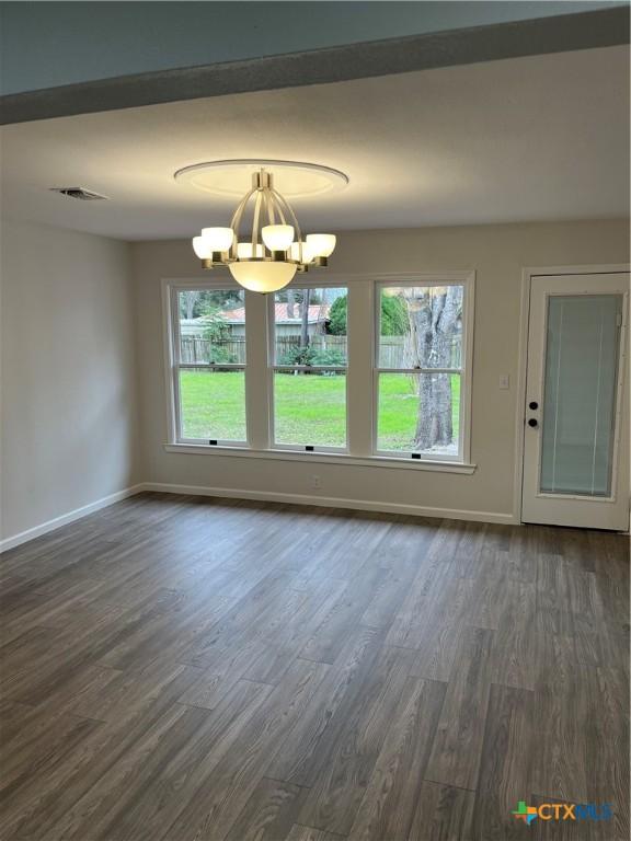 interior space with dark hardwood / wood-style floors, a wealth of natural light, and a notable chandelier