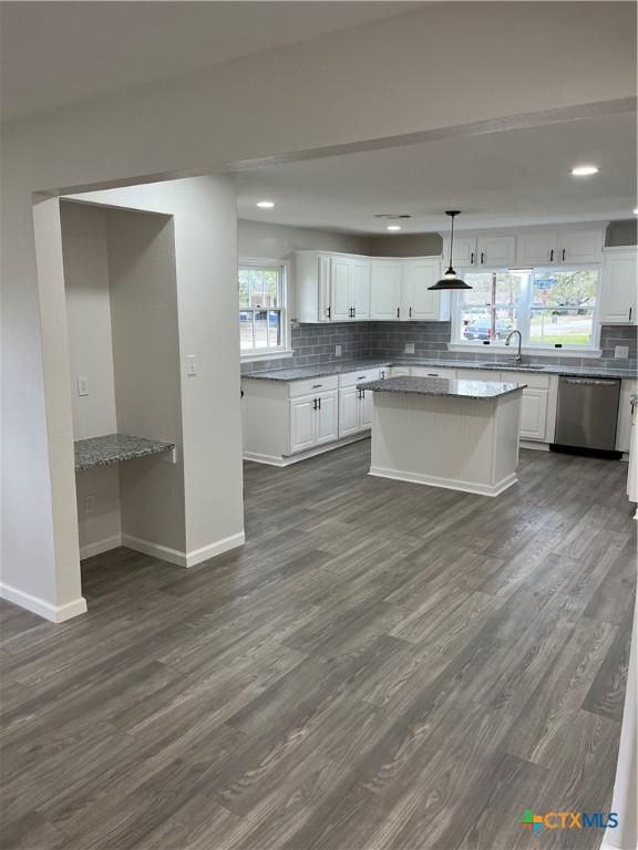 kitchen featuring hanging light fixtures, stainless steel dishwasher, white cabinets, and light stone counters