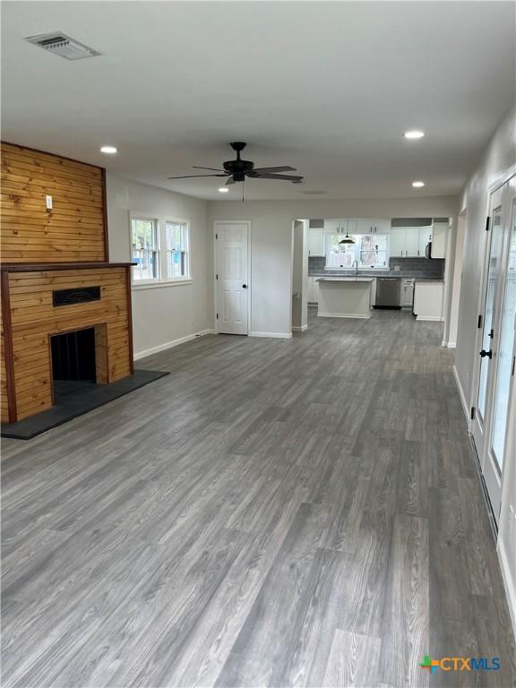 unfurnished living room with wood-type flooring and ceiling fan