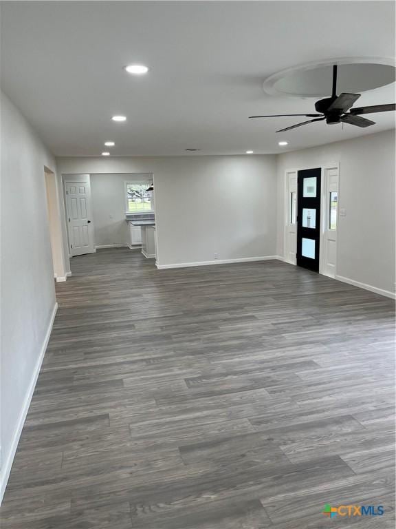 unfurnished living room featuring ceiling fan and dark hardwood / wood-style flooring