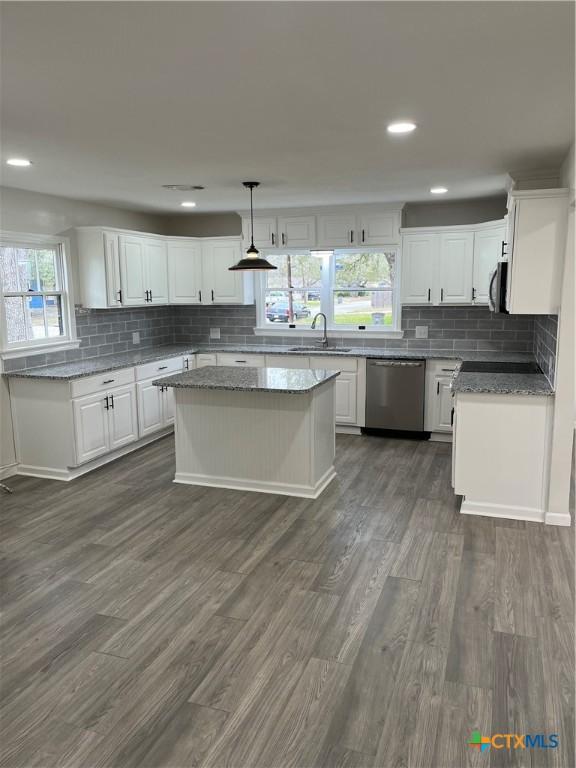 kitchen with stainless steel dishwasher, decorative light fixtures, a center island, and white cabinets