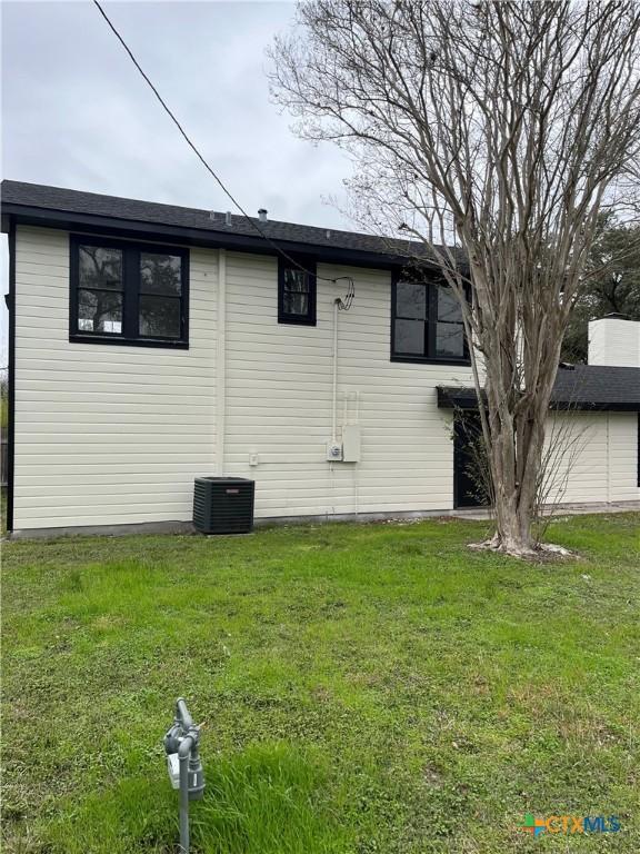 view of side of property featuring cooling unit and a lawn