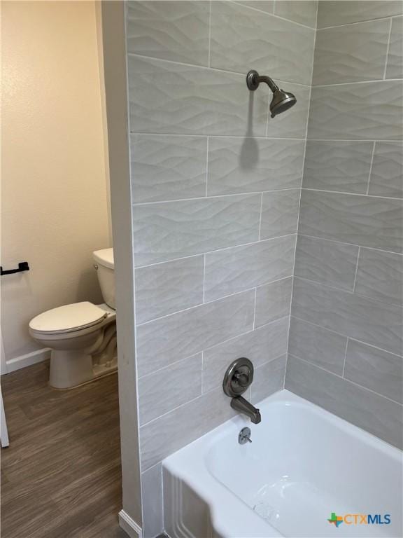 bathroom with hardwood / wood-style floors, tiled shower / bath, and toilet