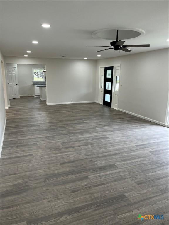 unfurnished living room featuring dark hardwood / wood-style flooring and ceiling fan