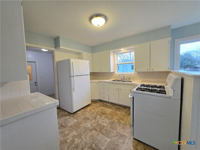 kitchen with white cabinetry, sink, tile countertops, and white appliances