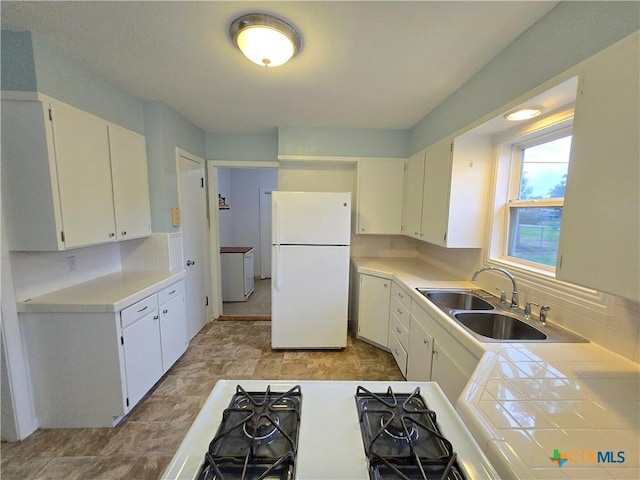 kitchen featuring sink, backsplash, white cabinets, and white fridge