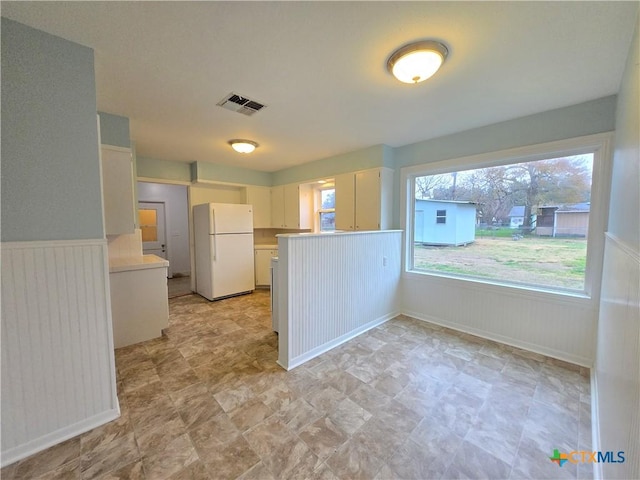 kitchen with white cabinetry, plenty of natural light, and white fridge