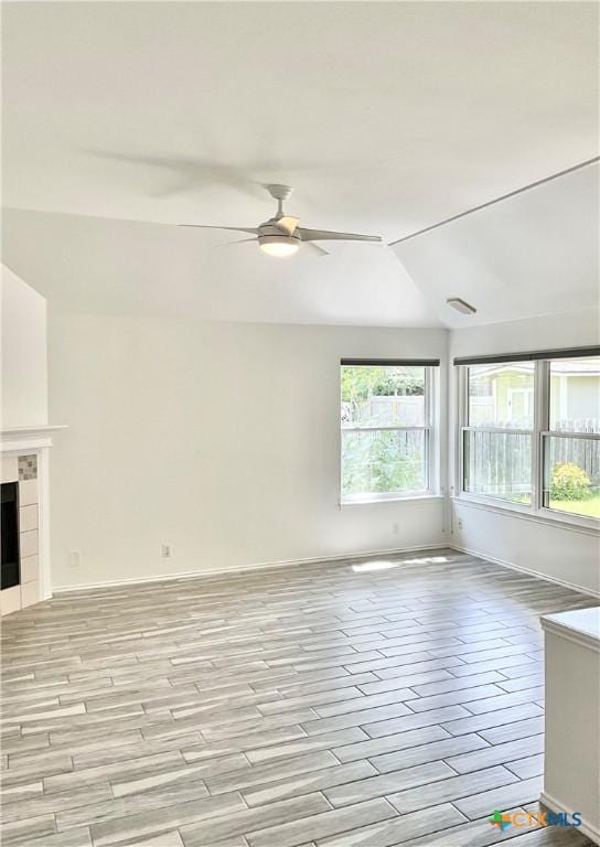 9100 Brimstone Ln, Austin, TX 78717 - unfurnished living room with ceiling fan, light wood-type flooring, vaulted ceiling, and a tile fireplace