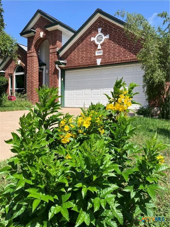 9100 Brimstone Ln, Austin, TX 78717 - traditional-style home featuring brick siding, concrete driveway, a front yard, and an attached garage