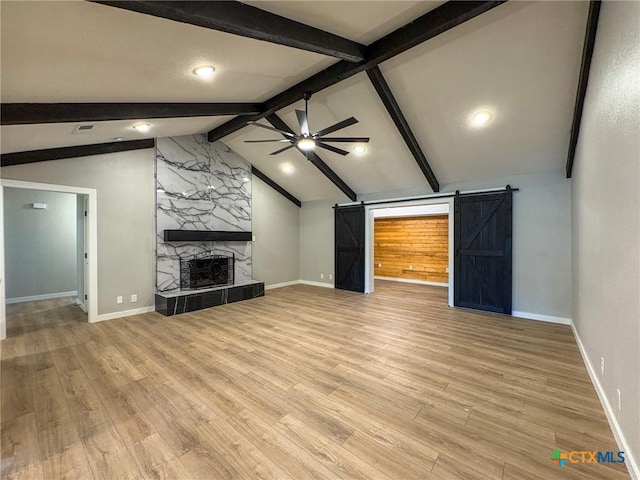 4310 Antelope Trl, Temple, TX 76504 - unfurnished living room with a ceiling fan, a barn door, light wood-style flooring, and a large fireplace