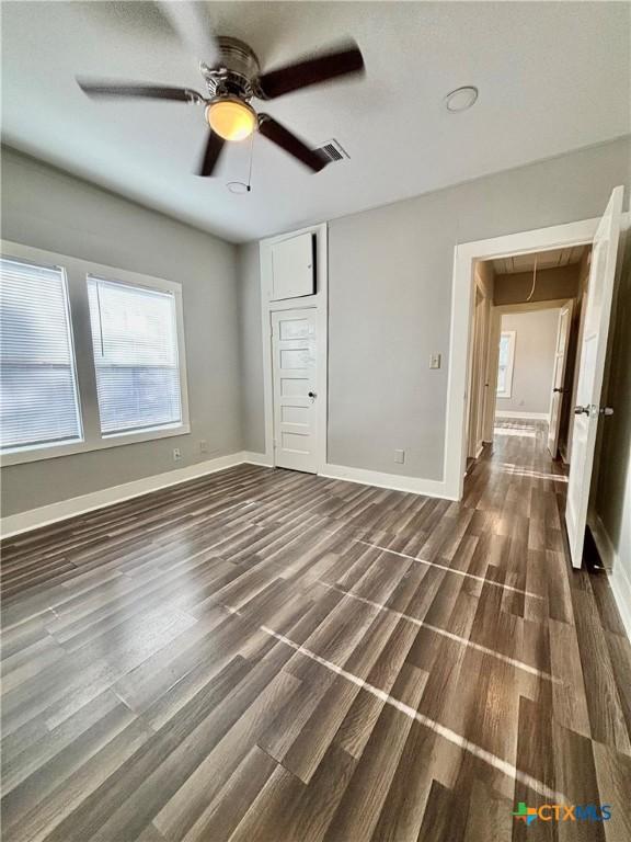 unfurnished bedroom featuring dark hardwood / wood-style floors, ceiling fan, and a closet