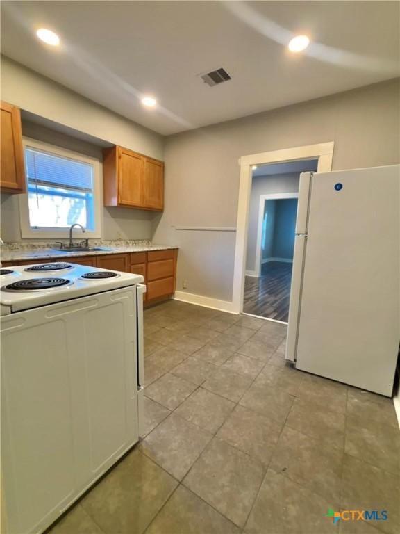 kitchen with sink, white appliances, and light tile patterned flooring