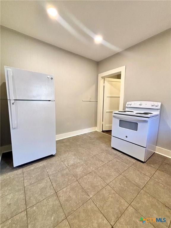 kitchen featuring light tile patterned flooring and white appliances