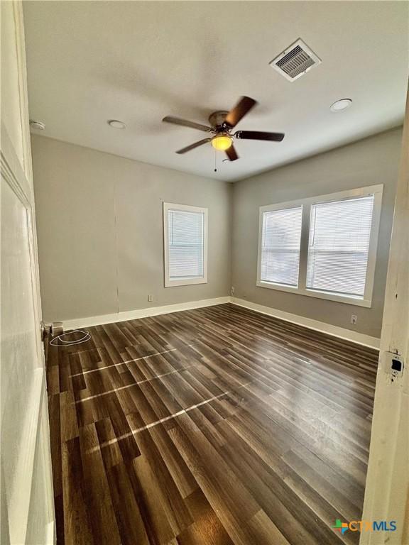 empty room featuring dark wood-type flooring and ceiling fan