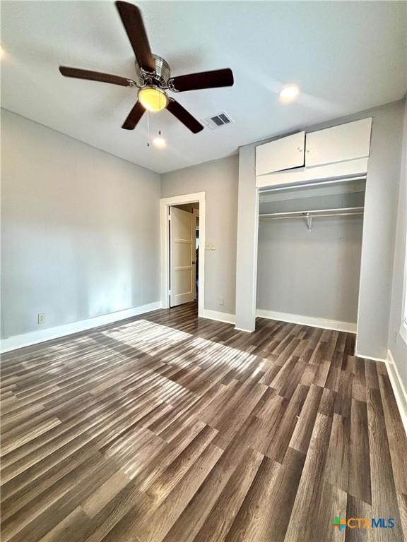 unfurnished bedroom featuring dark hardwood / wood-style floors, ceiling fan, and a closet