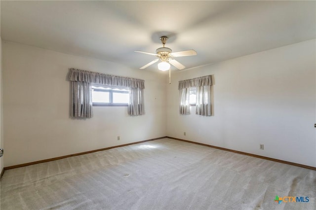 spare room with ceiling fan, baseboards, and light colored carpet