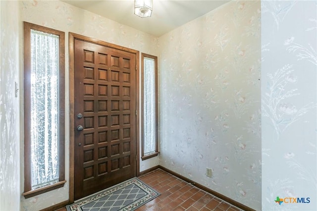 entryway with brick floor, baseboards, and wallpapered walls