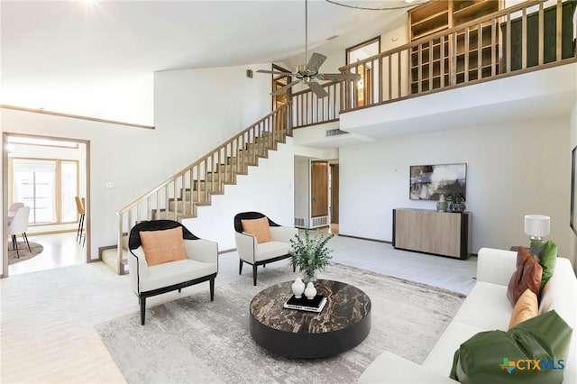 living area with visible vents, ceiling fan, a high ceiling, and stairs