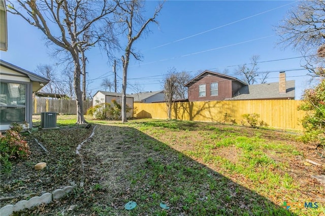 view of yard featuring a fenced backyard, a shed, and an outbuilding