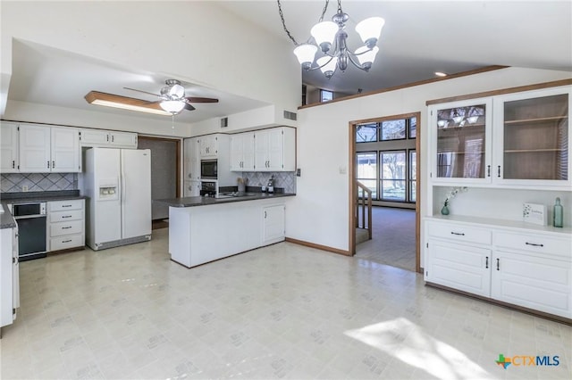 kitchen with white refrigerator with ice dispenser, dark countertops, stainless steel microwave, a peninsula, and white cabinetry