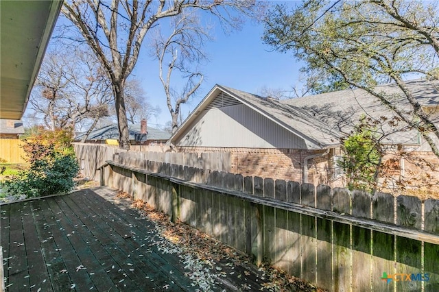 view of side of home featuring brick siding and fence