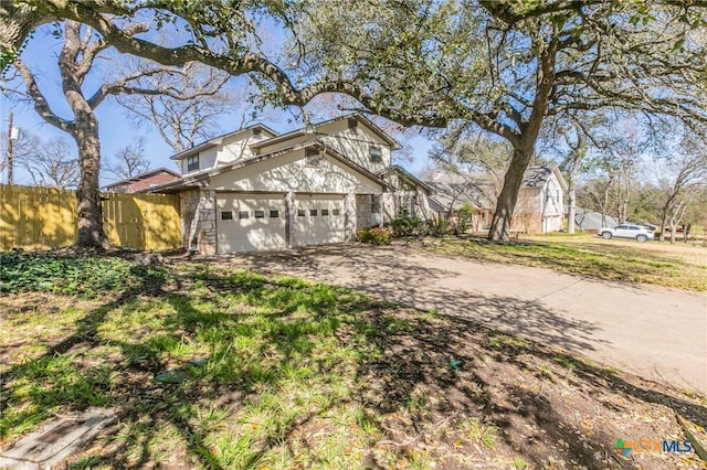 traditional-style home featuring driveway, an attached garage, and fence