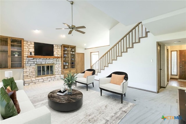 living room featuring ceiling fan, a fireplace, vaulted ceiling, stairs, and carpet