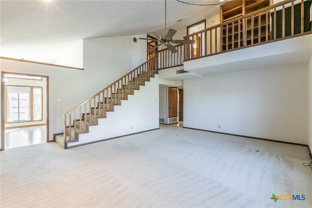 unfurnished living room with baseboards, ceiling fan, stairs, a high ceiling, and carpet floors