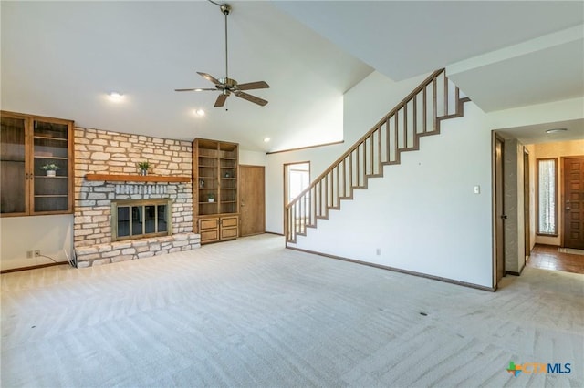 unfurnished living room featuring a large fireplace, carpet flooring, ceiling fan, baseboards, and stairs