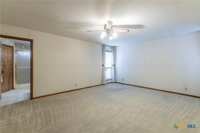 spare room with light carpet, ceiling fan, and baseboards