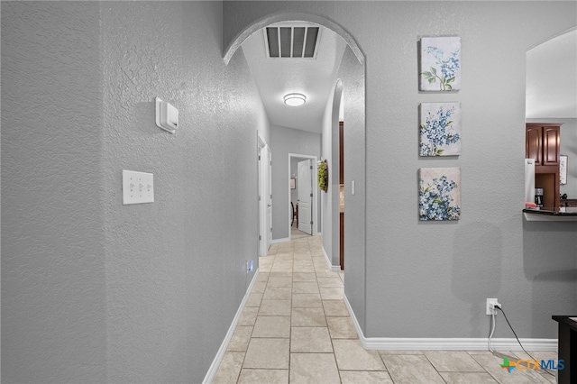 721 Gallagher Dr, Canyon Lake, TX 78133 - hall with a textured wall, arched walkways, light tile patterned floors, and baseboards