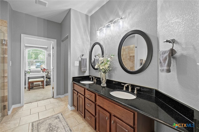 721 Gallagher Dr, Canyon Lake, TX 78133 - full bath with double vanity, a textured wall, tiled shower, tile patterned floors, and baseboards