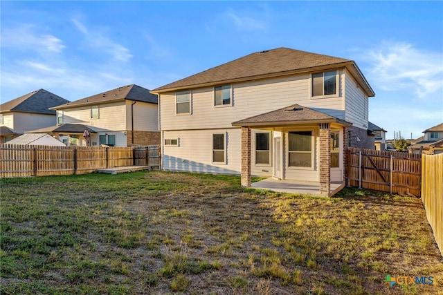 rear view of house featuring a lawn and a patio area