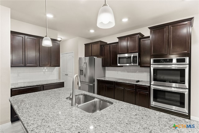 kitchen with appliances with stainless steel finishes, backsplash, hanging light fixtures, and sink