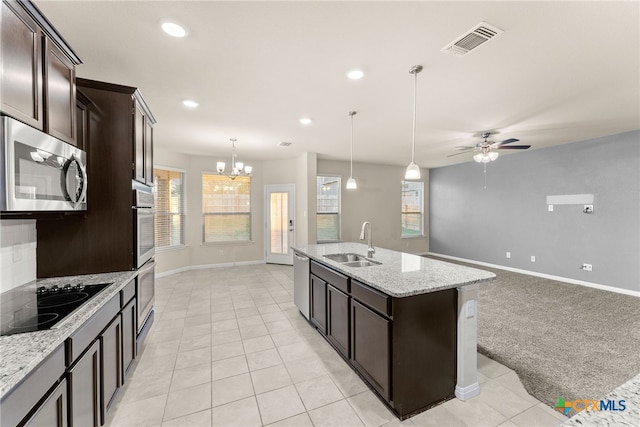 kitchen with ceiling fan with notable chandelier, stainless steel appliances, light colored carpet, sink, and a center island with sink