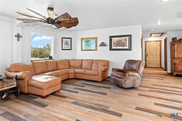 living room with ceiling fan, light hardwood / wood-style floors, and a textured ceiling