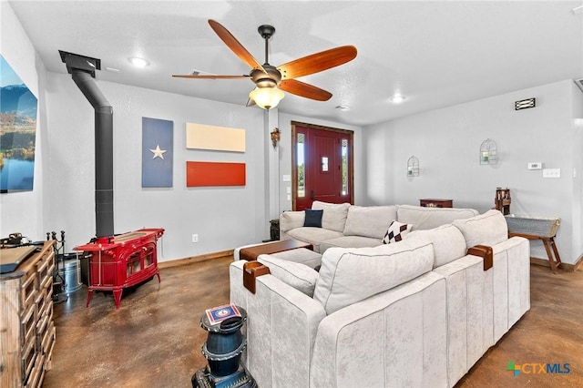 living room with a wood stove and ceiling fan