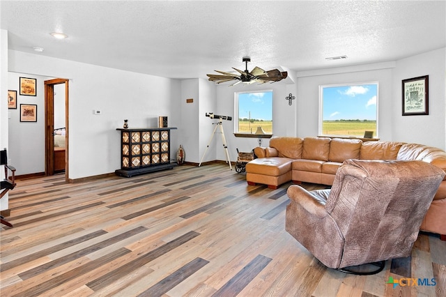 living room with ceiling fan, light hardwood / wood-style flooring, and a textured ceiling