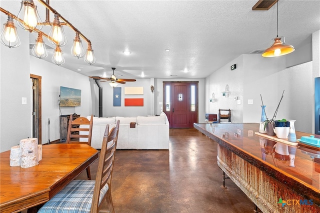 dining space featuring ceiling fan with notable chandelier and a textured ceiling