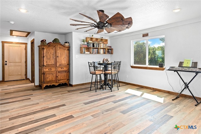 dining room featuring a textured ceiling, light hardwood / wood-style flooring, and ceiling fan