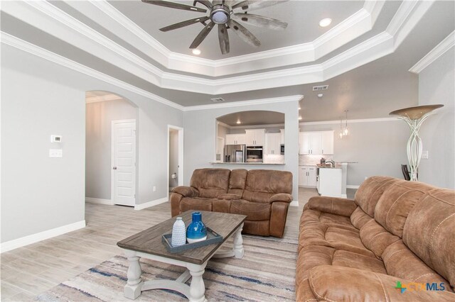 2109 Mercer St, Nolanville, TX 76559 - living room with crown molding, a ceiling fan, a raised ceiling, and arched walkways