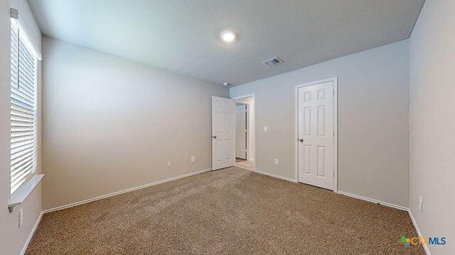 unfurnished bedroom with multiple windows and carpet